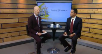 John Scholes, host of the Employment Law Show sits on a stool next to Employment Lawyer Lior Samfiru, Co-founding Partner at Samfiru Tumarkin LLP, with a coffee table and large flat screen TV between them, on the set of the well-known legal television show.