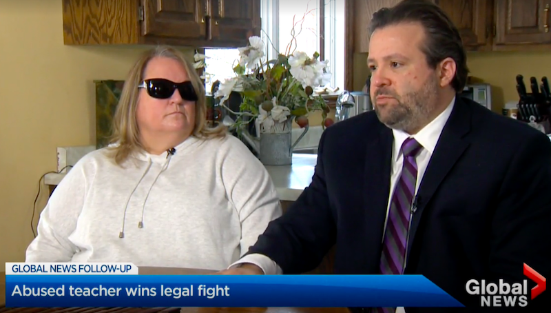 Julie Austin, teacher in the Simcoe Muskoka Catholic District School Board, sits next to her disability lawyer, James K. Fireman, at her kitchen table while wearing sunglasses as she shares her story with Global News.