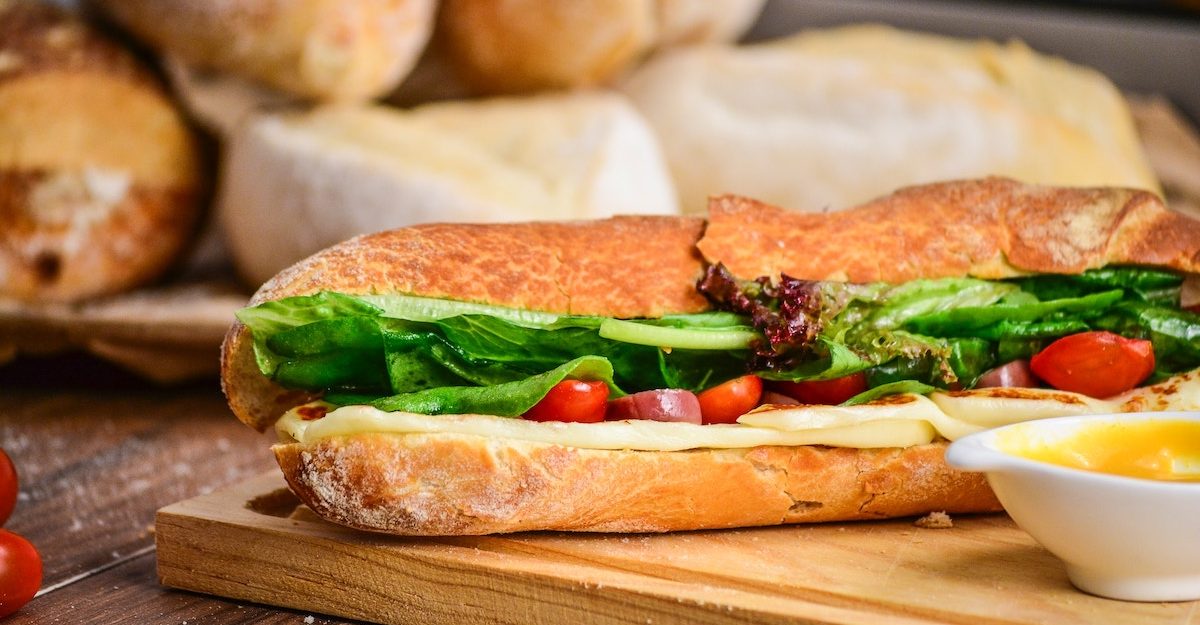 A delicious submarine sandwich, packed with meat, cheese and assorted vegetables, sits on a wooden cutting board. Subway Canada employees are entitled to severance pay when they lose their job.