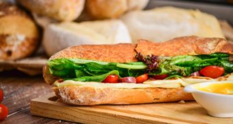 A delicious submarine sandwich, packed with meat, cheese and assorted vegetables, sits on a wooden cutting board. Subway Canada employees are entitled to severance pay when they lose their job.