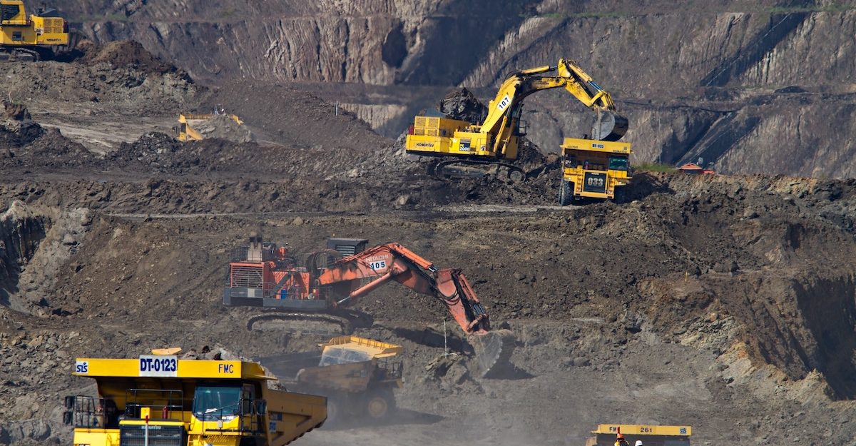 A number of dump trucks and excavators work in an open pit mine. Teck Resources employees are entitled to severance pay when they lose their job.