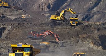 A number of dump trucks and excavators work in an open pit mine. Teck Resources employees are entitled to severance pay when they lose their job.