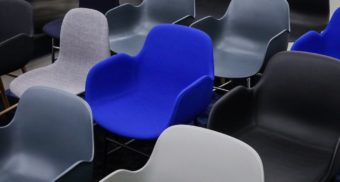 A blue chair is surrounded by grey chairs. Article owes severance pay to its fired employees.