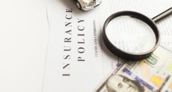 A magnifying glass, toy car and American money sit on top of a stack of papers titled 'Insurance Policy'. Insurance Bureau of Canada employees are entitled to severance when they lose their job.