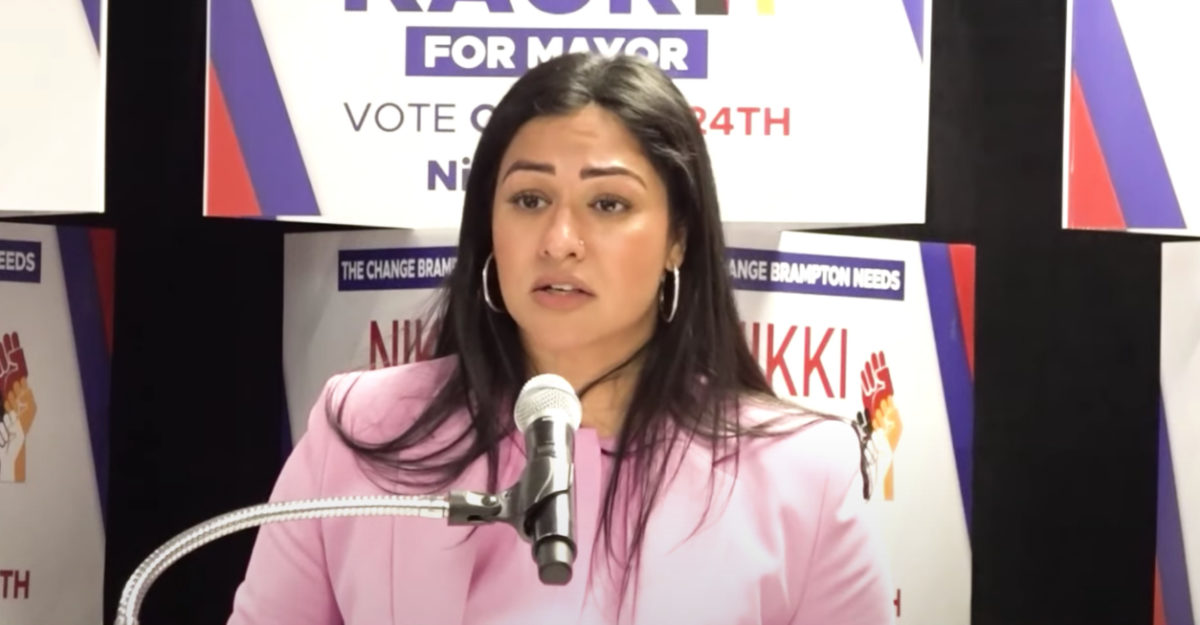 Brampton mayoral candidate Nikki Kaur stands in front of a microphone while speaking at an election event.