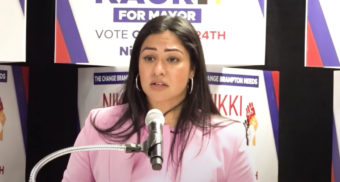 Brampton mayoral candidate Nikki Kaur stands in front of a microphone while speaking at an election event.