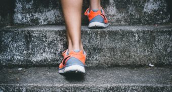 A close-up of a woman's legs climbing stairs, adorned with running shoes. Adidas owes severance pay when an employee is let go.