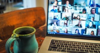 A videoconference featuring a dozen participants is shown on a laptop screen. Zoom employees are entitled to full severance pay when they lose their job.