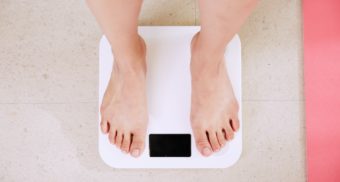 A bird's-eye view of someone's legs as the stand on a white bathroom scale. Jenny Craig employees are entitled to severance when they lose their job.