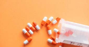 A pill bottle has been knocked over, spreading the half orange, half white capsules out across a light orange table. Haleon employees are entitled to severance pay.