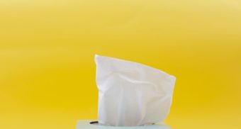 An image of a tissue sticking out of a box, set against a yellow background. Kimberly-Clark employees are entitled to severance when they lose their job.