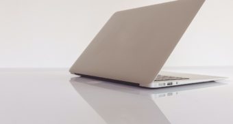 A grey laptop sits on a reflective glass table with the screen open slightly. Canada Computers employees are entitled to severance pay when they lose their job.