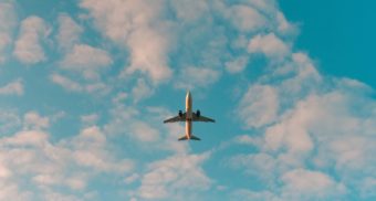 A view of an airliner's underbelly as it flies across a partly cloudy sky. Flight Centre employees are entitled to severance pay.