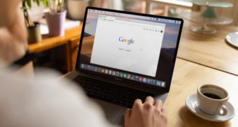 A man is looking at the Google homepage on his laptop browser. Google is laying off hundreds of global recruiters.