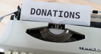 A white page sitting in a typewriter displays the word 'DONATIONS' in large font. Employees in the charitable sector are entitled to severance pay when they lose their job.