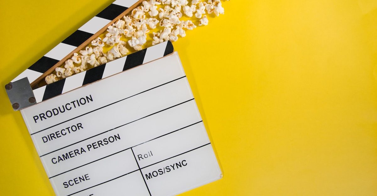 A traditional movie clapperboard lies flat on the ground with a handful of popcorn sitting in the agape clapper. Film and movie industry employees are entitled to severance pay.