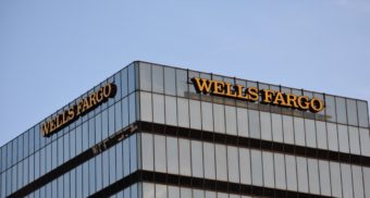 The Wells Fargo name adorns the top of a large office building topped with clear blue sky