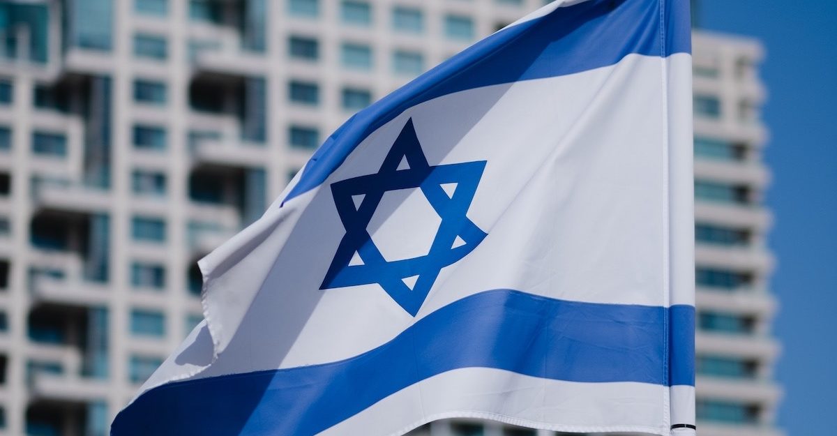 The Israeli flag is shown, held aloft by a strong breeze.