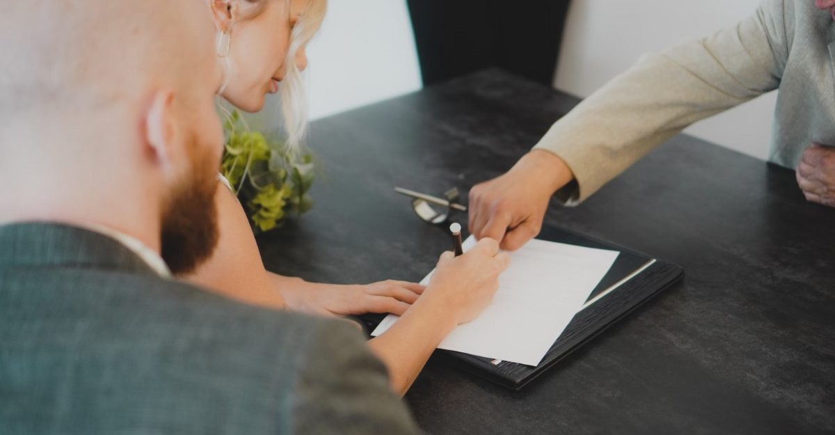 A photo of two people signing a document at a desk. (Photo: Annika Wischnewsky / Unsplash)