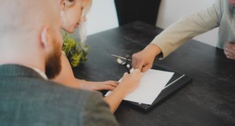 A photo of two people signing a document at a desk. (Photo: Annika Wischnewsky / Unsplash)