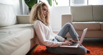 A photo of a person looking at a laptop while sitting on the floor. (Photo: Thought Catalog / Unsplash)