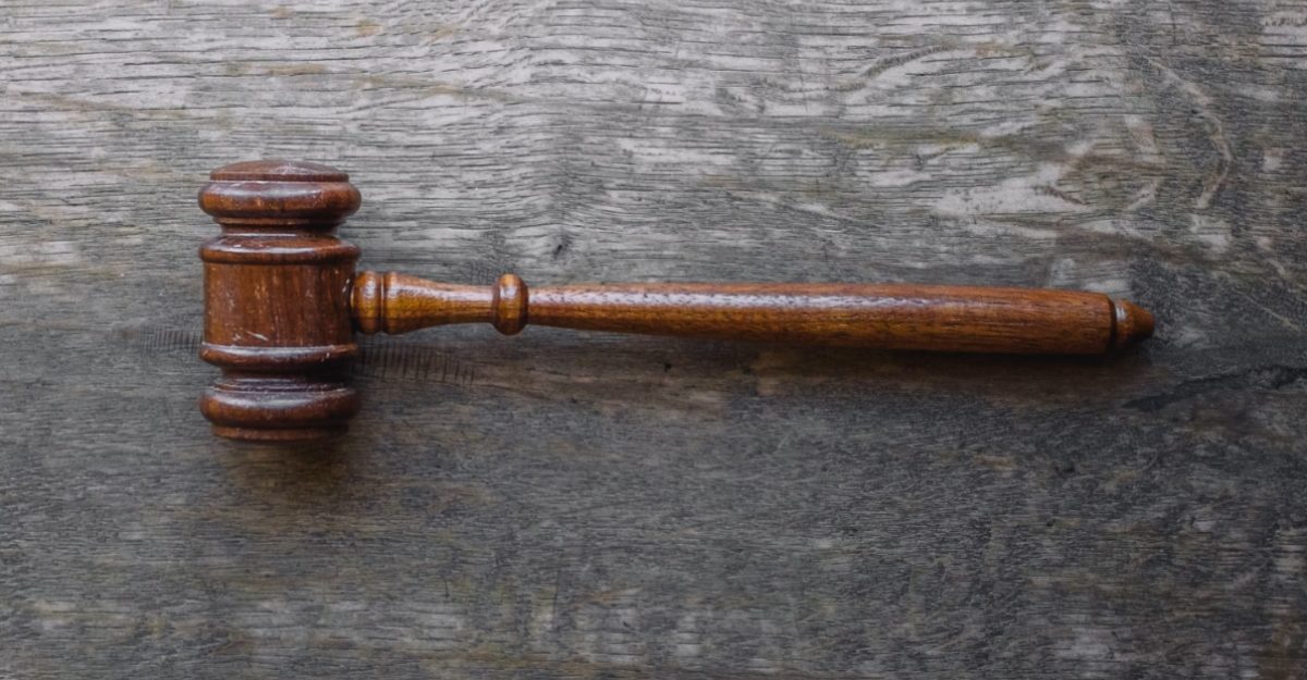 A photo of a brown gavel on a wooden table. (Photo: Wesley Tingey / Unsplash)