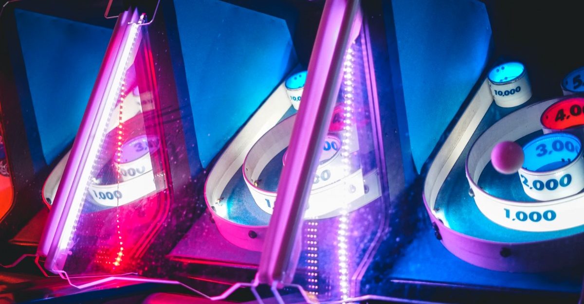 A photo of skee-ball machines with neon lights. (Photo: Rhett Wesley / Unsplash)