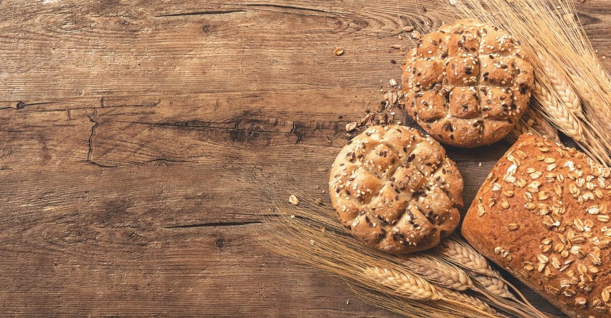 A photo of bread and wheat on a wooden table. (Photo: Ales Krivec / Unsplash)