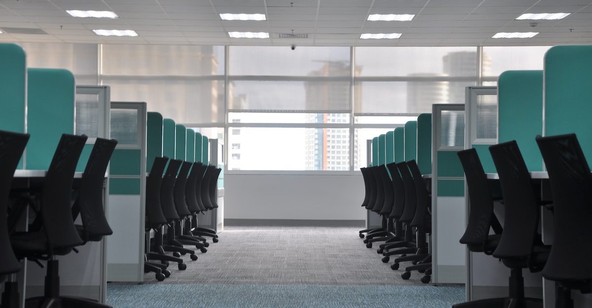 Rows of empty workstations sit on either side of the aisle.