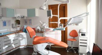 A dentist's chair sits in the middle of a neat and clean dental office.