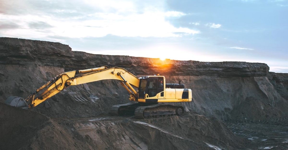 A photo an excavator on the side of a cliff. (Photo: Artyom Korshunov / Unsplash)