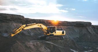 A photo an excavator on the side of a cliff. (Photo: Artyom Korshunov / Unsplash)