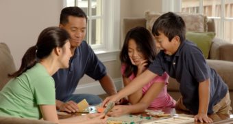 A family of four play a board game in the living room on Family Day in Ontario.