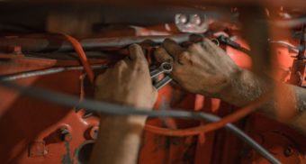 A photo of a person working on an orange machine. (Photo: Nina Mercado / Unsplash)