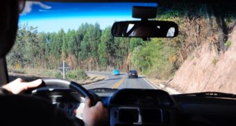 A photo of a person driving behind two other vehicles on a road. (Photo: Rodrigo dos Reis / Unsplash)