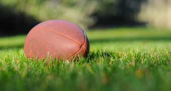 A photo of a football on a lawn. (Photo: Ben Hershey / Unsplash)