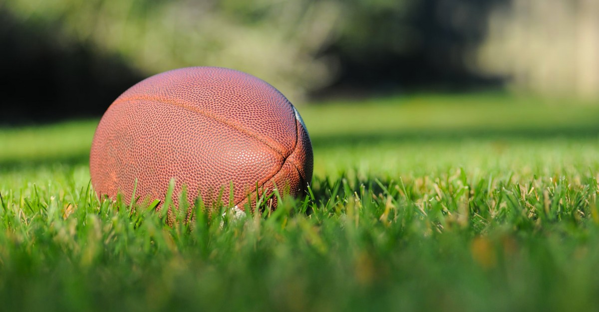 A photo of a football on a lawn. (Photo: Ben Hershey / Unsplash)