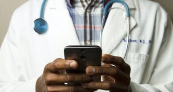 A photo of a doctor looking at a phone. (Photo: National Cancer Institute / Unsplash)