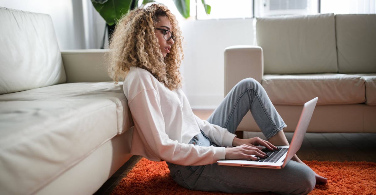 A photo of a person looking at a laptop while sitting on the floor. (Photo: Thought Catalog / Unsplash)