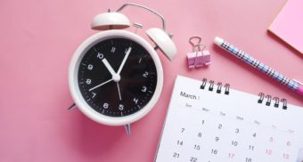 A photo of a pink clock and calendar on a pink table. (Photo: Towfiqu barbhuiya / Unsplash)