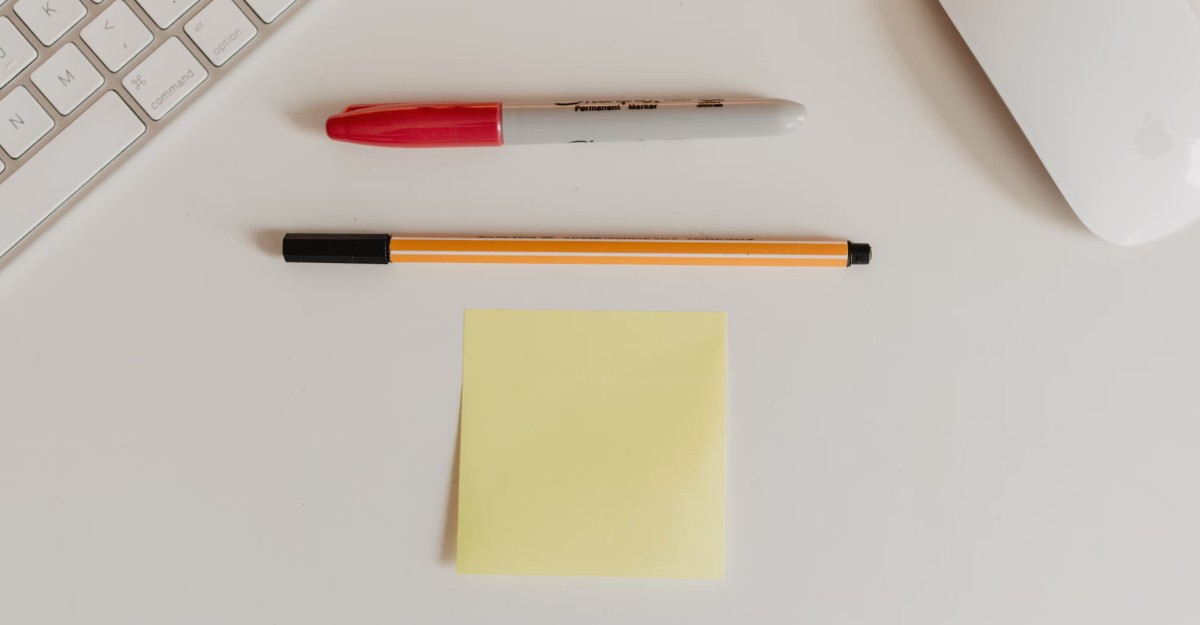 A photo of a sharpie marker, pen, and a notepad on a table. (Photo: Kelly Sikkema / Unsplash)