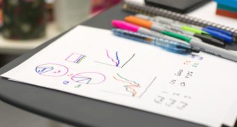 A photo of a piece of paper beside multiple sharpie markers on a desk. (Photo: Jason Coudriet / Unsplash)