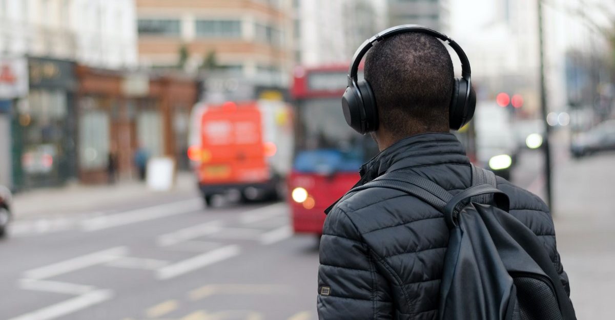 A photo of a person wearing headphones and looking out at a street. (Photo: Henry Be / Unsplash)