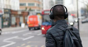 A photo of a person wearing headphones and looking out at a street. (Photo: Henry Be / Unsplash)