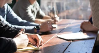 A photo of staff attending a meeting and taking notes. (Photo: Dylan Gillis / Unsplash)