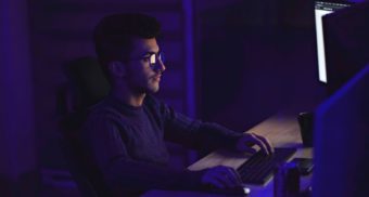 A photo of a person looking at multiple computer screens. (Photo: Mohammad Rahmani / Unsplash)