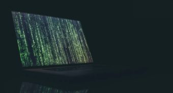 A photo of a laptop with code moving across the screen. (Photo: Markus Spiske / Unsplash)