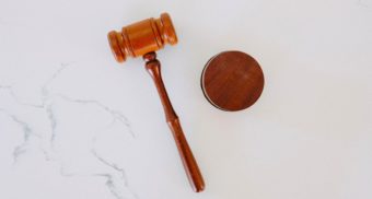 A photo of a wooden gavel on a white marble backdrop. (Photo: Tingey Injury Law Firm / Unsplash)