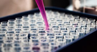 A photo of a person pouring a chemical into various vials. (Photo: Louis Reed / Unsplash)