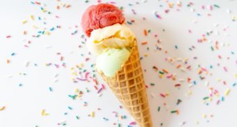 A photo of ice cream in a cone with sprinkles all over the table. (Photo: Courtney Cook / Unsplash)